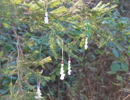 Verschiedene Christbaumanhänger aus Salzteig auf Tannenbaum im Wald.